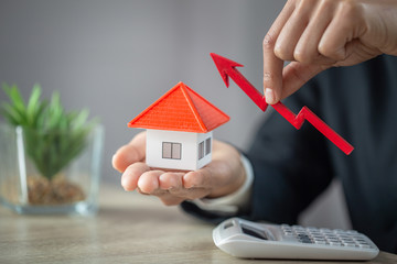 Businessman Holding  Graph Over The Increasing House Miniature, Real estate investment,investment mortgage finance and home loan business, growth and money.