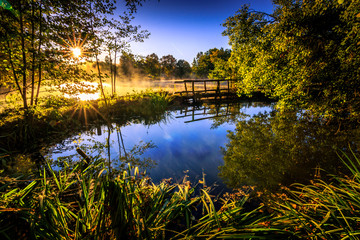 Beautiful summer sunrise at a small lake framed by nature.  a beautiful blue sky with its white clouds creates a special atmosphere.  the lake is called Meerpfuhl and is located in the Taurus,.