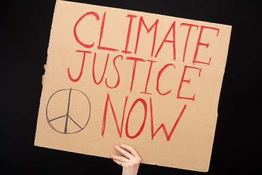 Partial View Of Woman Holding Placard With Climate Justice Now Lettering Isolated On Black, Global Warming Concept