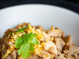 Fried pork with garlic and pepper Thai Recipes,Garnish with coriander,On a white plate and a black background