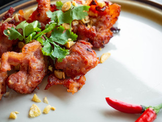 Fried Pork with Garlic Thai food Ingredients of pork ribs,Decorate the dish with red chilies, garlic and coriander on a white plate.