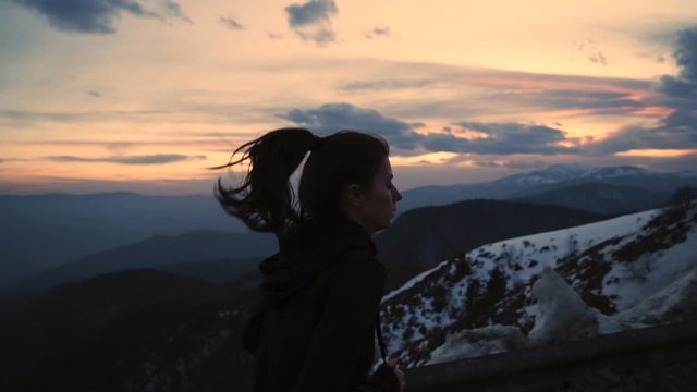 Determined young woman running in cold winter night with scenic sunset in the background