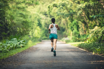 Woman runner running at summer park trail . Healthy fitness woman jogging outdoors.