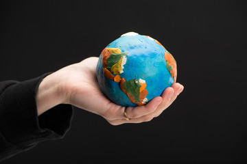 Cropped view of plasticine globe in female hand isolated on black, global warming concept