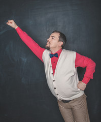 Funny nerd man in superhero pose on blackboard background