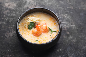 Tom yum, a spicy soup with coconut milk, shrimps and mushrooms. Traditional Japanese cuisine. Eastern cuisine. Soup on a dark background