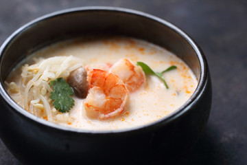 Tom yum, a spicy soup with coconut milk, shrimps and mushrooms. Traditional Japanese cuisine. Eastern cuisine. Soup on a dark background