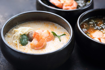 Tom yum, a spicy soup with coconut milk, shrimps and mushrooms. Traditional Japanese cuisine. Eastern cuisine. Soup on a dark background