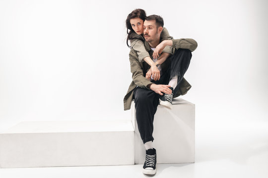 One whole. Trendy fashionable couple isolated on white studio background. Caucasian woman and man posing in basic minimal stylish clothes. Concept of relations, fashion, beauty, love. Copyspace.