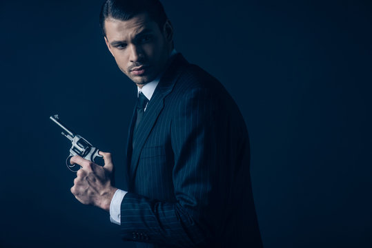 Side view of gangster with revolver on dark background
