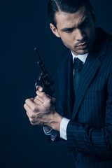 Gangster holding weapon with clenched hands on dark blue