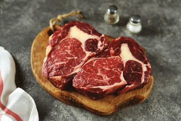 Fresh raw rib eye steak on a wooden board. Organic food. 