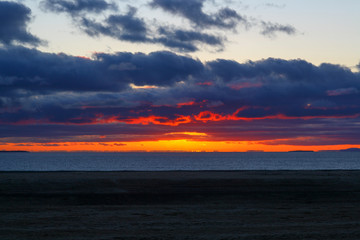 Beautiful sunset over the ocean with waves moving to shore on the North Shore of Iceland.