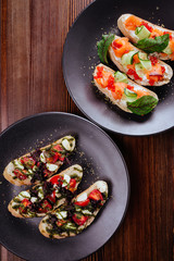 Italian Appetizer Bruschetta with roasted tomatoes, mozzarella cheese, garlic and herbs on wooden table