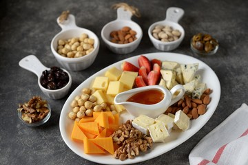 Various types of cheeses with olives, nuts, fruits and honey. Appetizer for a wine party.