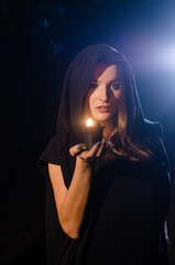 Young girl in a long black coat fire night