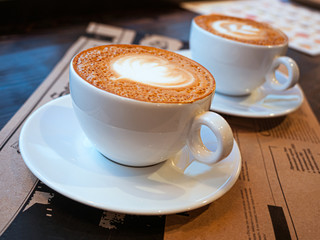 Two cups of cappuccino on a table in a cafe. drawing heart on Latte coffee froth. Delicious coffee for breakfast