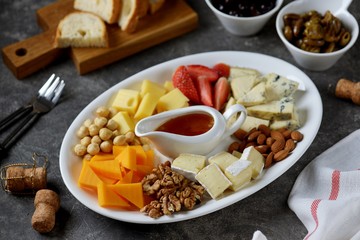 Various types of cheeses with olives, nuts, fruits and honey. Appetizer for a wine party.