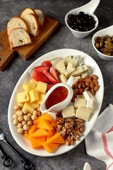 Various types of cheeses with olives, nuts, fruits and honey. Appetizer for a wine party.