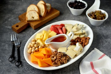 Various types of cheeses with olives, nuts, fruits and honey. Appetizer for a wine party.