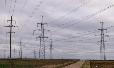 landscape with wet earth road and high voltage line