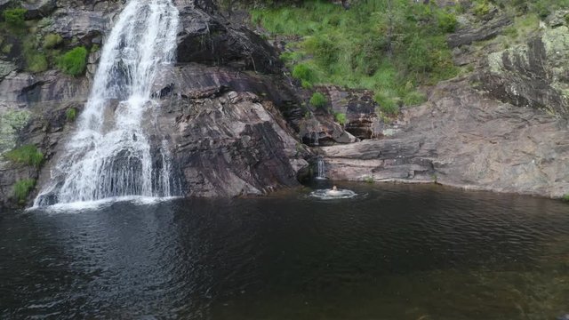 Man swimming drone aerial view in most beautiful waterfall Fisgas de Ermelo in Mondim de Basto, Portugal