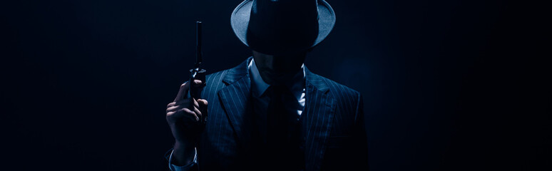 Fototapeta Silhouette of gangster raising gun on dark blue background, panoramic shot obraz