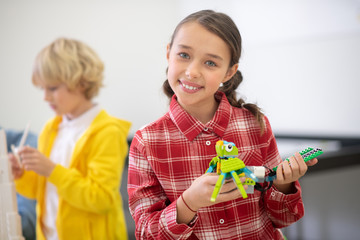 Girl holding buildable bird and smiling, boy building tower