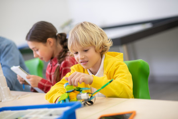 Obraz premium Boy playing with buildable bird, girl checking notes