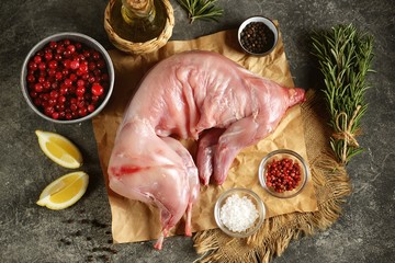 Fresh raw rabbit on an iron tray with cranberry, rosemary, pink pepper and sea salt