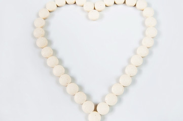 Medicine pills concept on gray background. Round pills in the shape of a heart on a white background close-up and copy space.