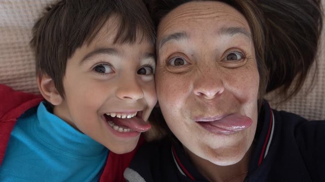 4K Selfie of resembling mother and son putting out their tongues