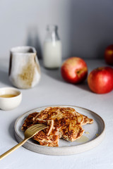 Homemade buckwheat apple pancakes with honey on light background. Pescajounes.  Hard light, deep shadow. Selective focus