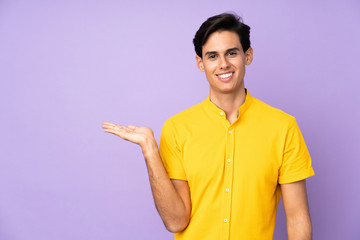 Man over isolated purple background holding copyspace imaginary on the palm to insert an ad