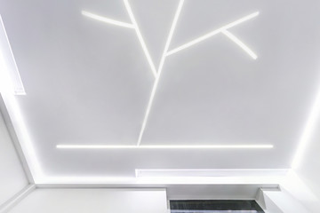 looking up on suspended ceiling with halogen spots lamps and drywall construction in empty room in...