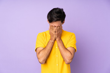 Man over isolated purple background with tired and sick expression