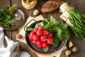 Fresh spring radish with wild garlic parsley and quail eggs on a wooden background. Ingredients for the salad.