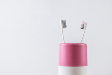 Blue and pink toothbrushes in a pink cup, isolated on white background with copy space 