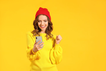 Young woman with mobile phone on color background