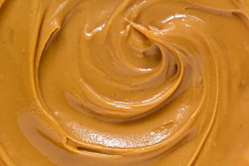 Peanut butter texture background. Creamy smooth brown nut spread swirl close up. Delicious dark natural food paste macro top view - Powered by Adobe