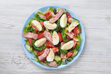 Classic Nicoise salad on a blue plate. View from above. Close-up.