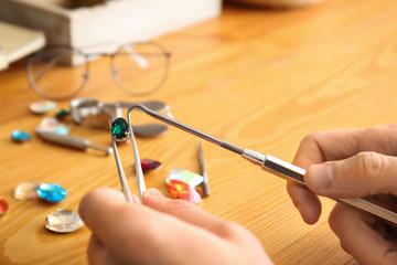 Jeweler examining gemstone in workshop, closeup