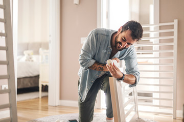 Man putting wheels on a baby crib.