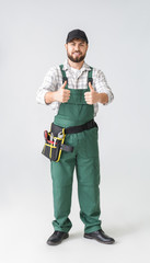 Handsome plumber showing thumb-up on light background