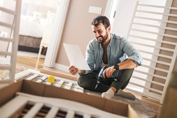 Man reading installing instructions for a baby crib.