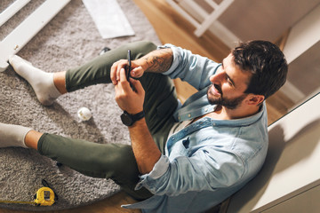 Man taking a break from assembling a baby crib.