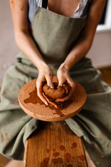 Beautiful inspiring sexy attractive pretty girl working in a workshop, doing her hobby modeling on a Potter's wheel handwork professional creativity art woman at work, girl stained with paint and clay