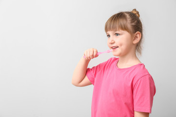 Little girl with tooth brush on light background