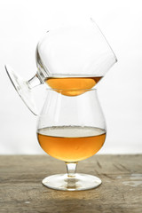 Cognac \ whiskey in cognac glass on wooden table, golden color spirits splashing on white background