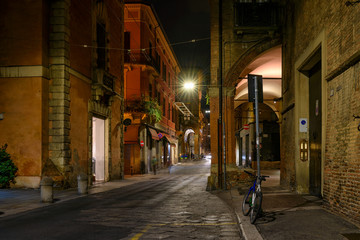 Fototapeta premium Old narrow street in Bologna at night, Emilia Romagna, Italy. Architecture and landmark of Bologna. Cozy cityscape of Bologna.
